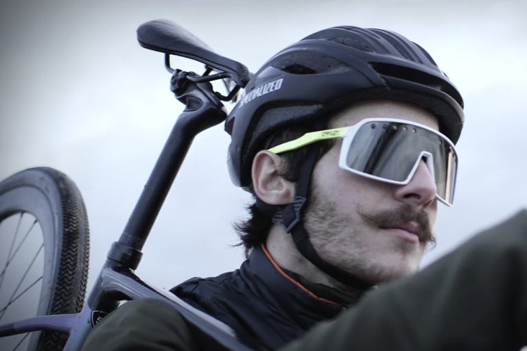 Homme avec casque et lunettes portant son vélo sportif